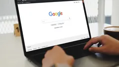 Hands typing on a laptop showing the Google search page representing Google Ads services